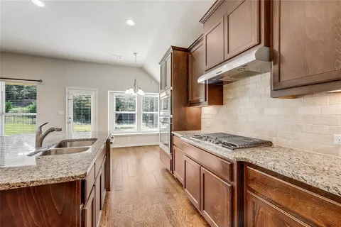 a kitchen with granite countertop a sink stove and cabinets
