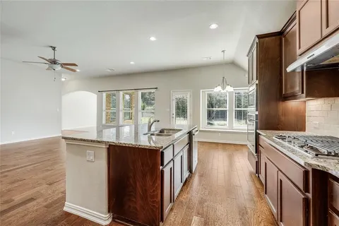 a kitchen with stainless steel appliances granite countertop a stove and a wooden floors