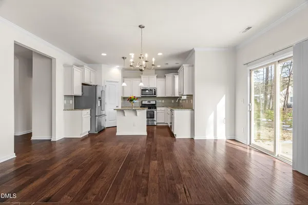 a view of a kitchen with wooden floor and stainless steel appliances