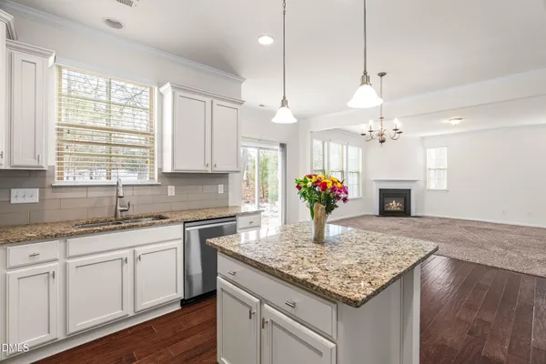 a kitchen with kitchen island granite countertop a stove center island a sink cabinets and wooden floor