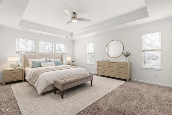 a spacious bedroom with a bed a dresser and windows