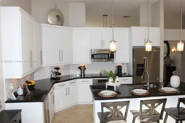 a kitchen with stainless steel appliances a sink a stove a table and chairs