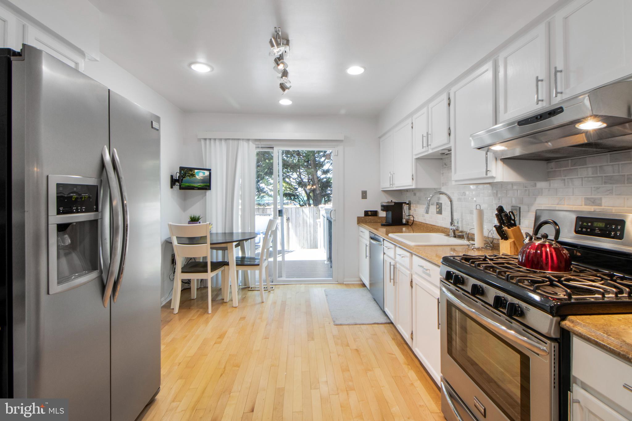 14432 Bakersfield Court Silver Spring, MD 20906 - Photo 17 of 60 a kitchen with stainless steel appliances granite countertop a stove a refrigerator a sink dishwasher and white cabinets with wooden floor