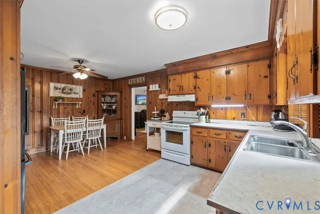 a kitchen with stainless steel appliances granite countertop a stove top oven a sink dishwasher a dining table and chairs with wooden floor