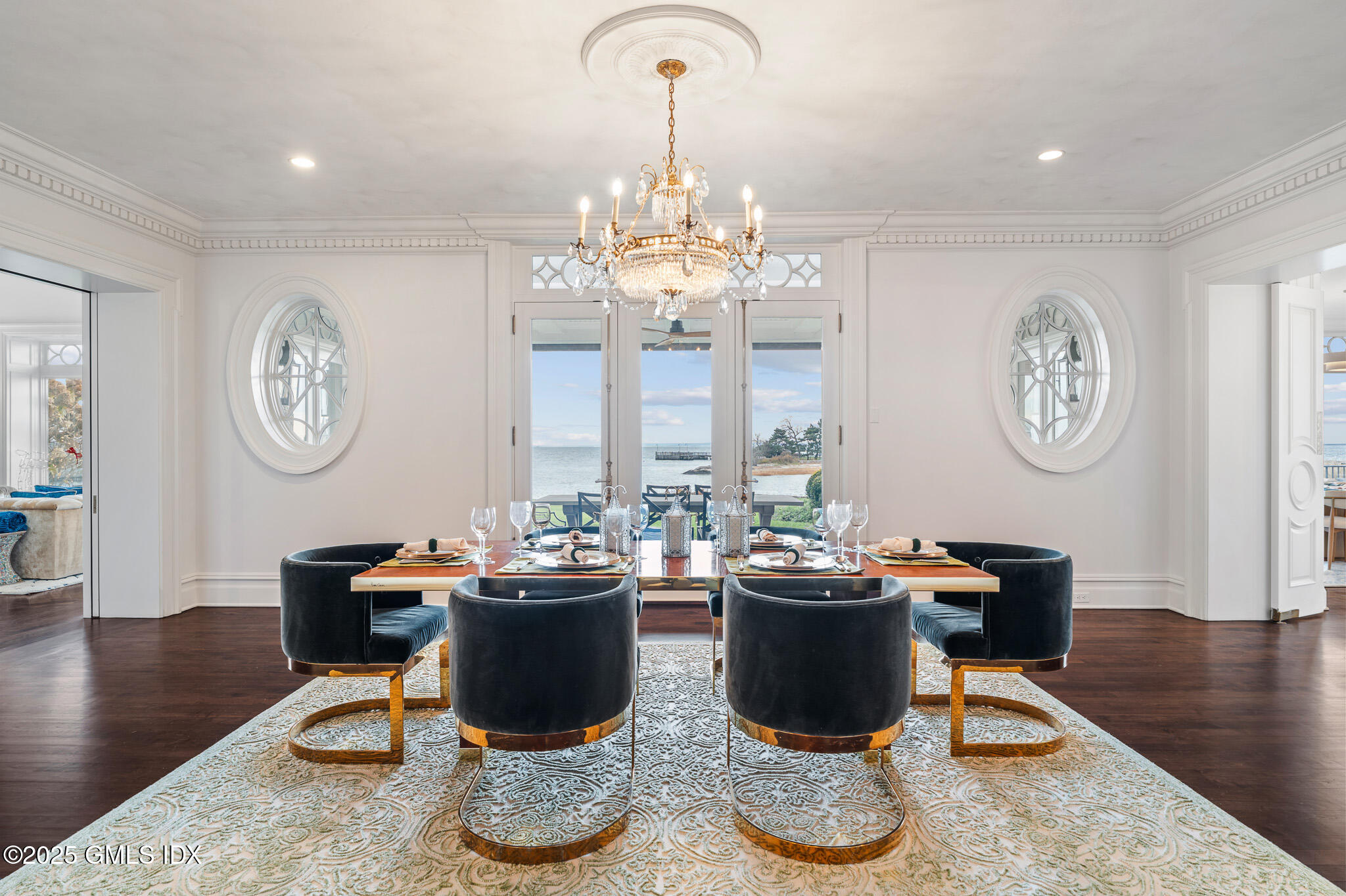545 Indian Field Road Greenwich, CT 06830 - Photo 13 of 39 a dining room with wooden floor a chandelier a wooden table and a clock