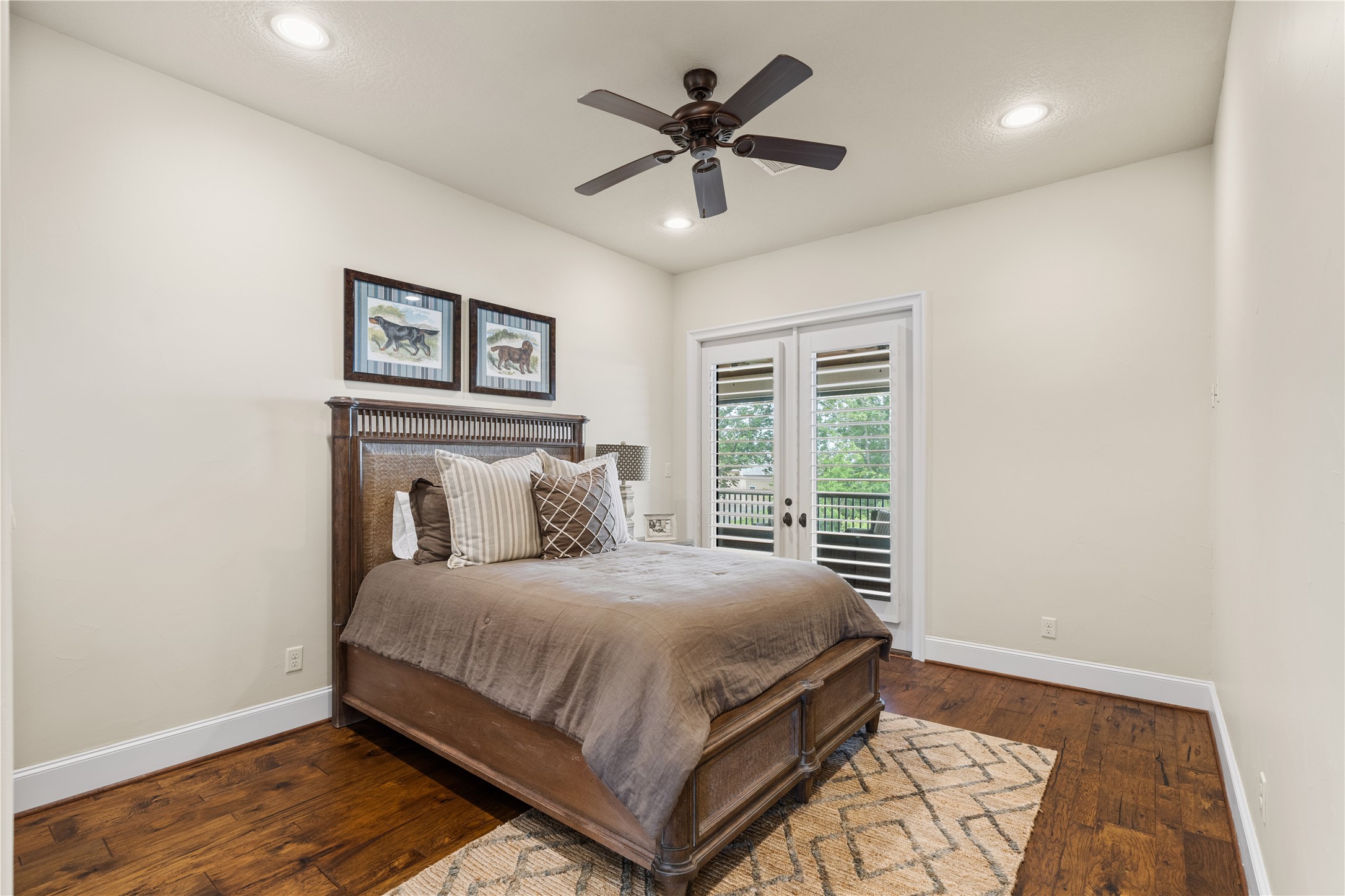 12349 Longmire Trace Conroe, TX 77304 - Photo 27 of 48 Bright bedroom with hardwood floors, recessed lighting, ceiling fan, and French doors with shutters.