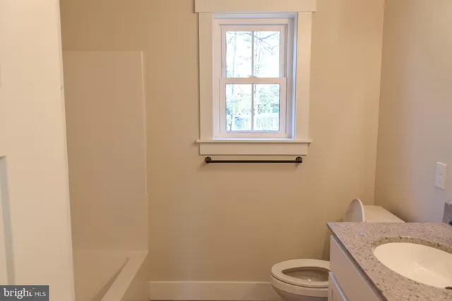 a bathroom with a granite countertop toilet and a sink