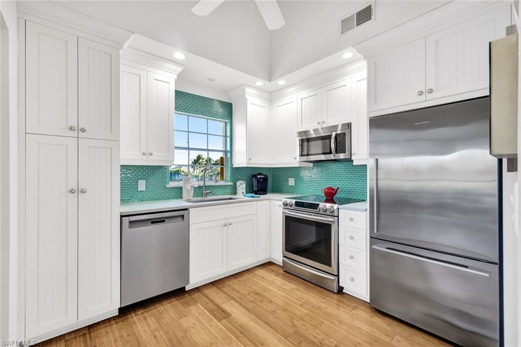 14985 Rivers Edge Court, Unit 236 Fort Myers, FL 33908 - Photo 13 of 33 a kitchen with white cabinets and stainless steel appliances