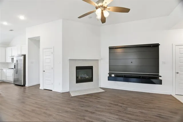 a view of an empty room with a fireplace and wooden floor