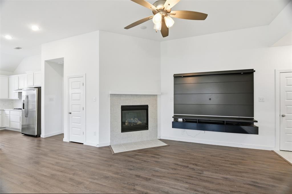 3910 Rochelle Lane Crandall, TX 75114 - Photo 11 of 32 a view of an empty room with a fireplace and wooden floor