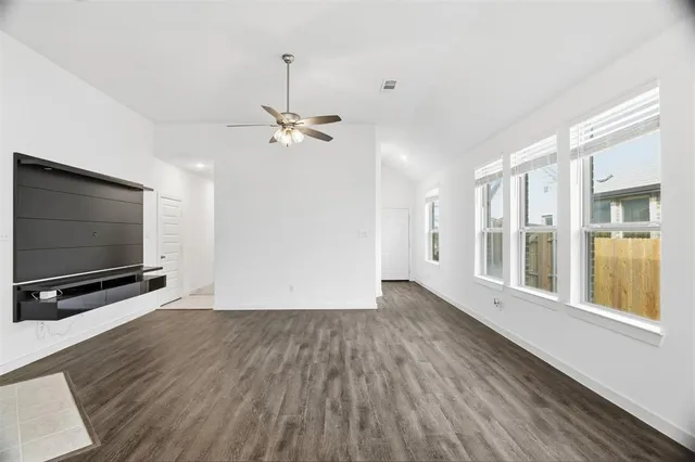 a view of an empty room with a window and wooden floor