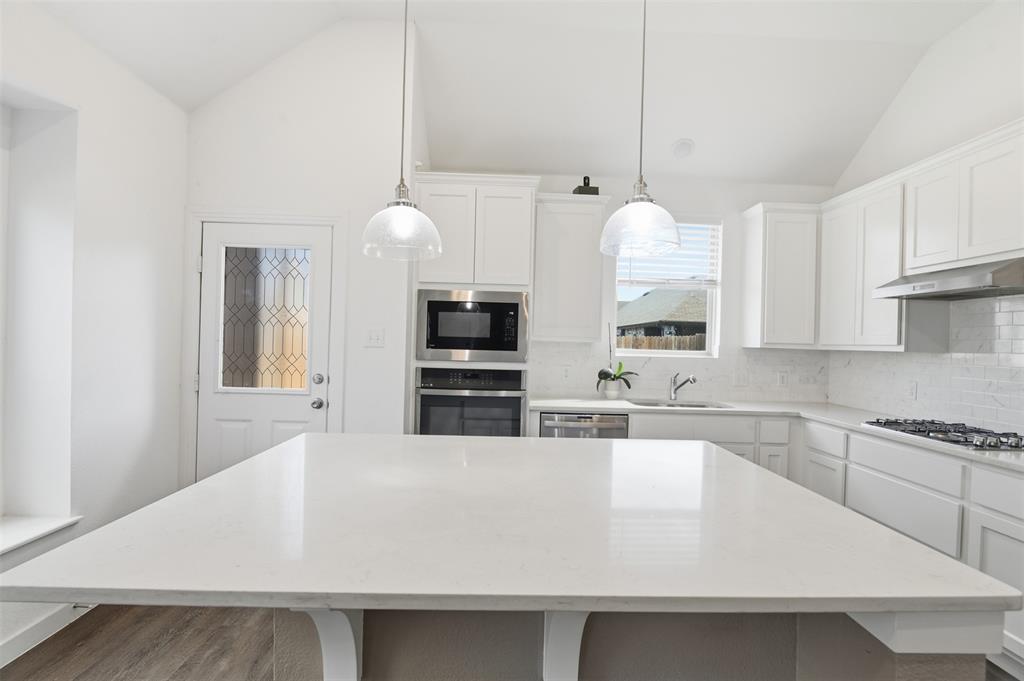 3910 Rochelle Lane Crandall, TX 75114 - Photo 14 of 32 a kitchen with stainless steel appliances a white counter top space cabinets and wooden floor