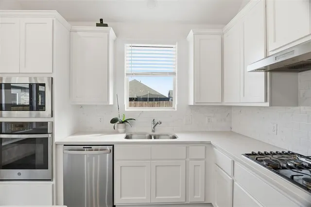 a kitchen with white cabinets and a stove