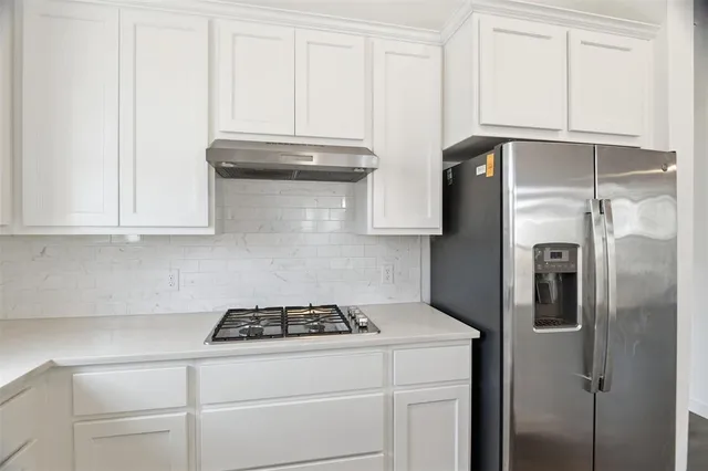 a kitchen with stainless steel appliances granite countertop a refrigerator a stove and white cabinets