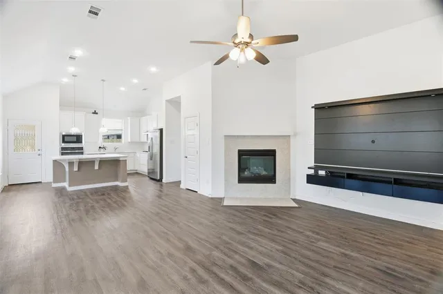 a view of a kitchen with furniture a ceiling fan and wooden floor