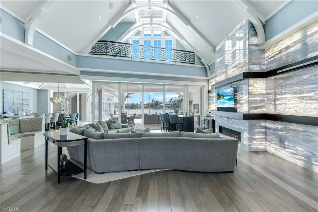 350 Springline Drive Naples, FL 34102 - Photo 2 of 33 Living area featuring high vaulted ceiling, wood finished floors, a large fireplace, and a chandelier