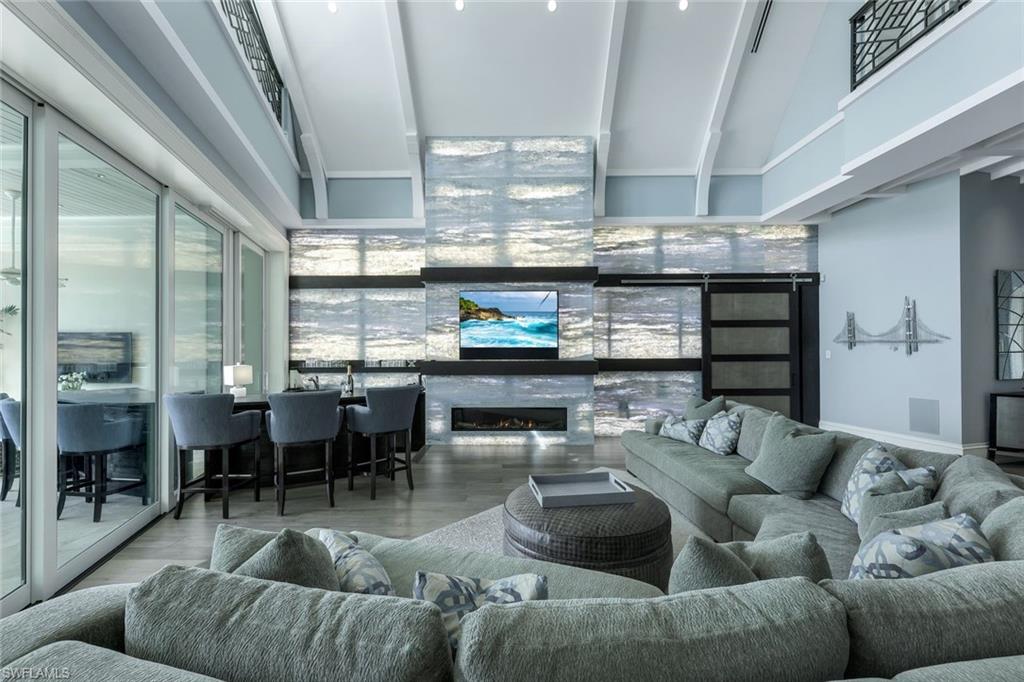 350 Springline Drive Naples, FL 34102 - Photo 3 of 33 Living area with wood finished floors, a high ceiling, and a glass covered fireplace