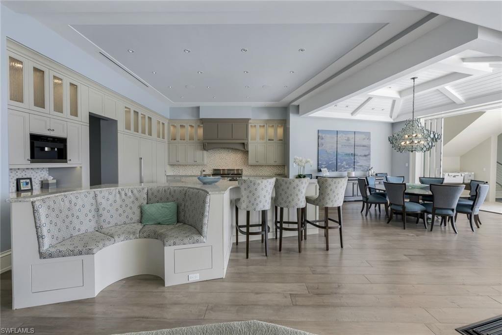 350 Springline Drive Naples, FL 34102 - Photo 4 of 33 Kitchen with tasteful backsplash, glass insert cabinets, beamed ceiling, a kitchen bar, and light wood-style floors