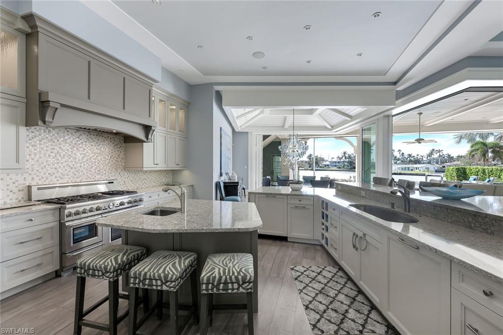 350 Springline Drive Naples, FL 34102 - Photo 5 of 33 Kitchen featuring light stone countertops, a tray ceiling, double oven range, a chandelier, and a breakfast bar area