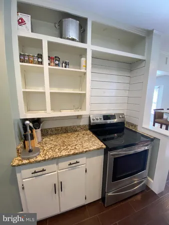 a kitchen with granite countertop a stove and cabinets
