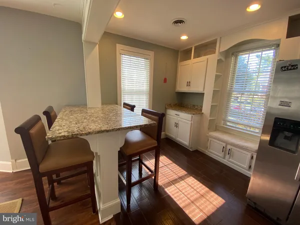 a kitchen with stainless steel appliances granite countertop a stove top oven a sink a dining table and chairs with wooden floor