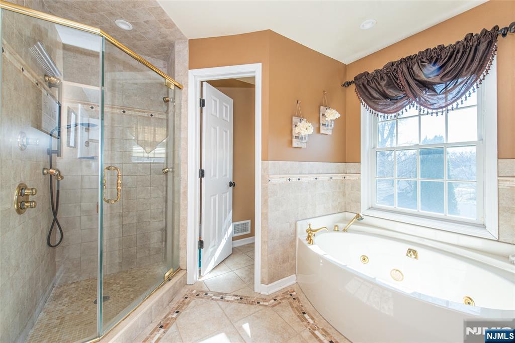 18 Stonycroft Road Wayne, NJ 07470 - Photo 20 of 40 a bathroom with a bathtub a shower a sink and a window