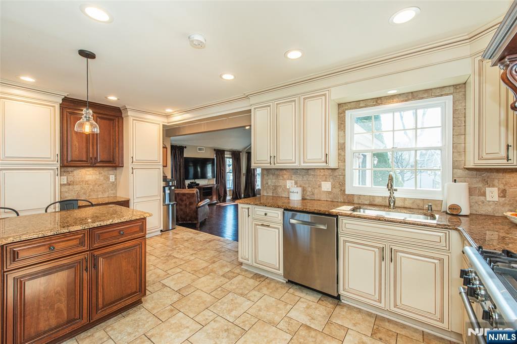 18 Stonycroft Road Wayne, NJ 07470 - Photo 7 of 40 a kitchen with stainless steel appliances granite countertop a stove top oven a sink dishwasher a dining table and chairs with wooden cabinets