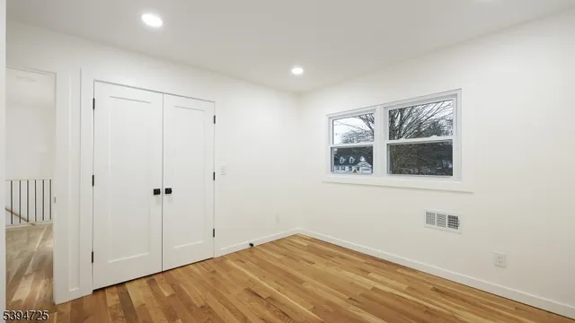 a view of empty room with window and wooden floor
