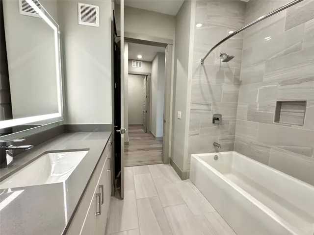 a bathroom with a tub a sink and a large mirror