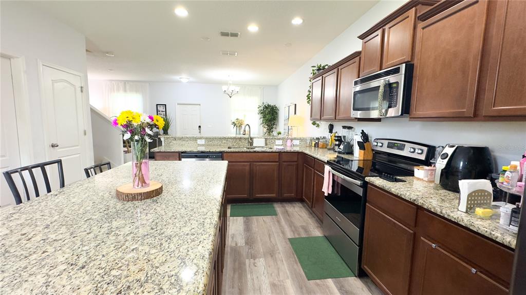 1217 Seburn Road Apopka, FL 32703 - Photo 42 of 61 a kitchen with stainless steel appliances granite countertop a sink dishwasher a stove top oven a refrigerator with wooden cabinets and floor