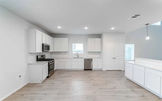 a large kitchen with cabinets a sink and appliances