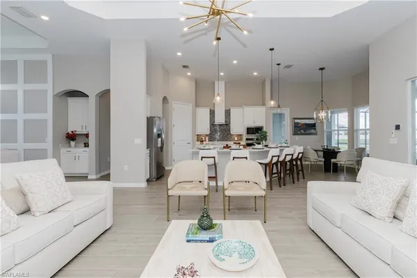a living room with furniture kitchen view and a chandelier