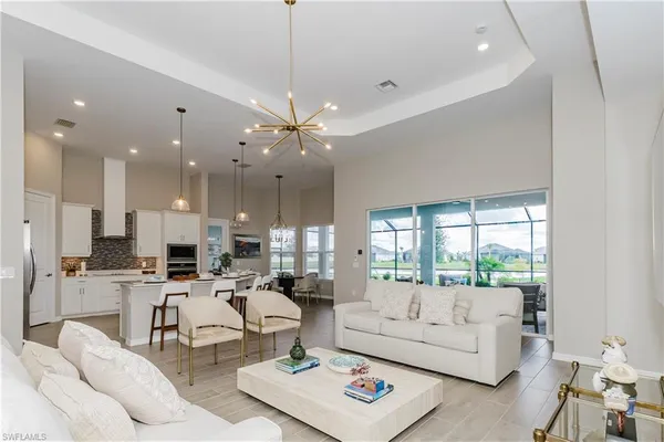 a living room with furniture kitchen view and a chandelier
