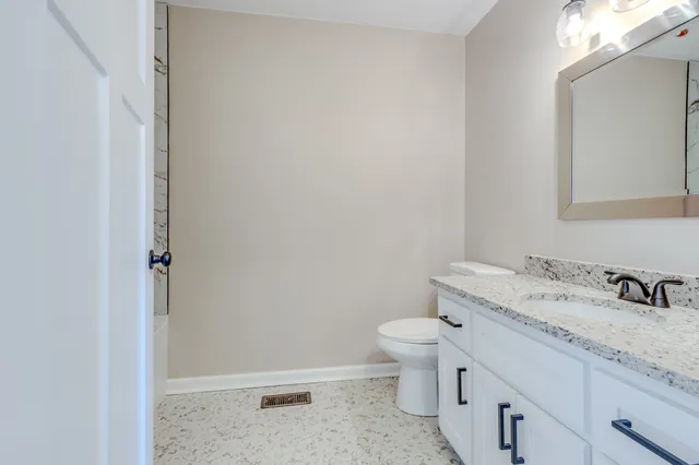 an empty room with wooden floor ceiling fan and windows