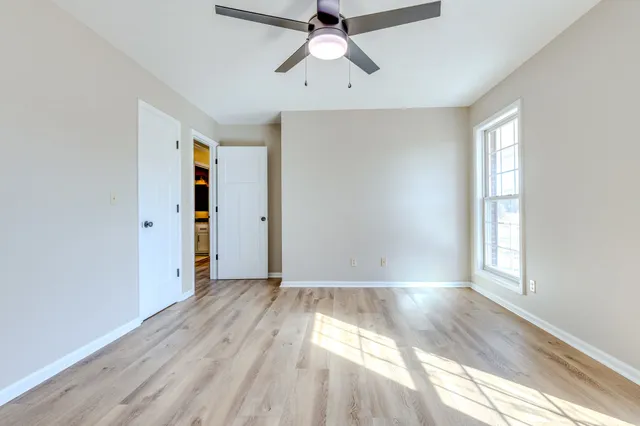 an empty room with wooden floor and a ceiling fan