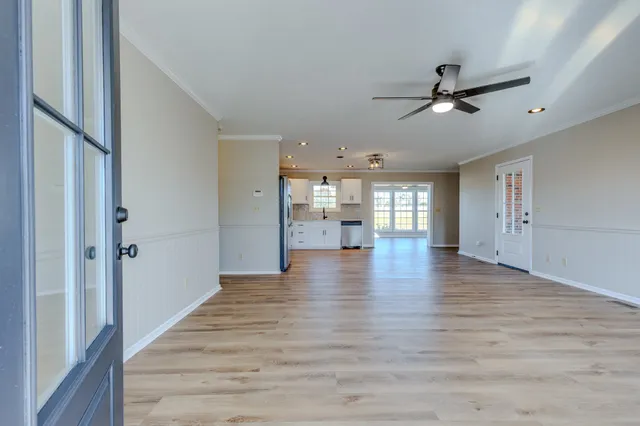 a view of an empty room with a kitchen and a window
