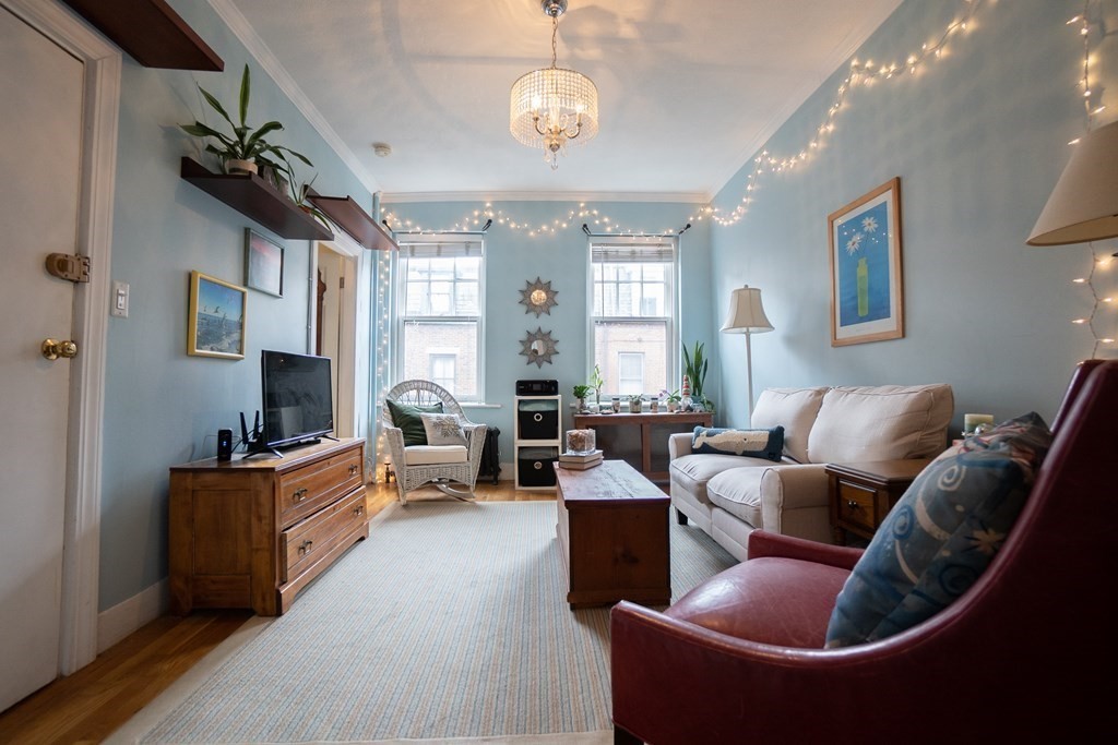 11 Irving Street, Unit 6 Boston, MA 02114 - Photo 1 of 14 a living room with furniture a fireplace and a chandelier