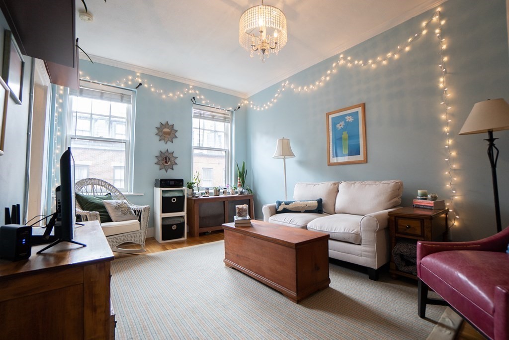 11 Irving Street, Unit 6 Boston, MA 02114 - Photo 2 of 14 a living room with furniture chandelier and a large window