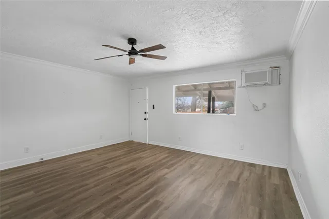an empty room with wooden floor ceiling fan and windows