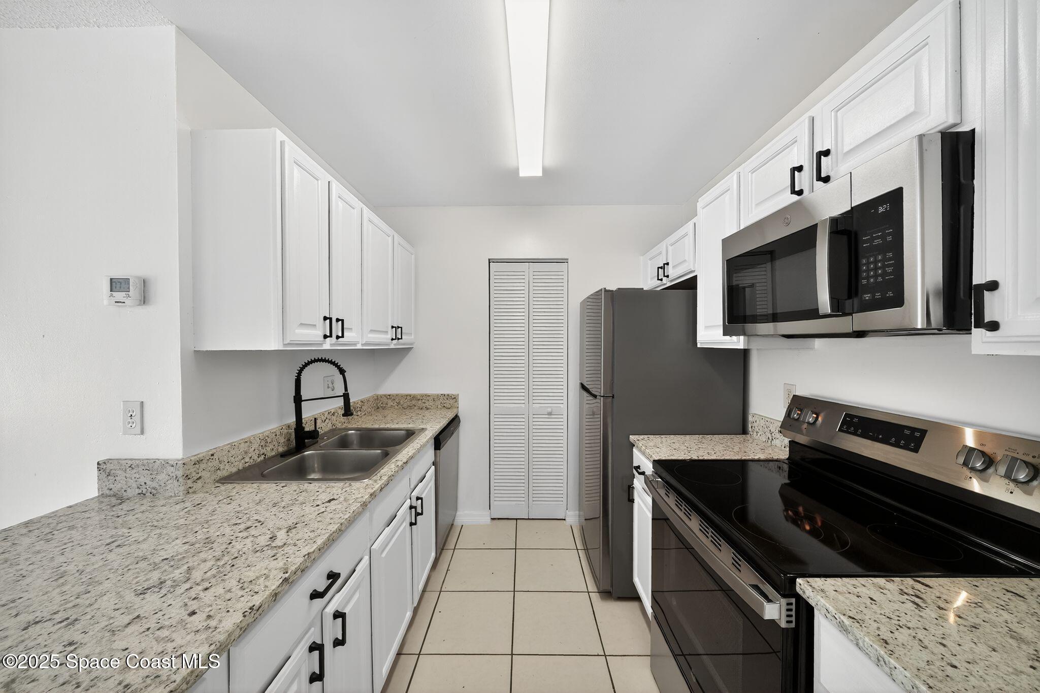 410 Thor Avenue Southeast, Unit 103 Palm Bay, FL 32909 - Photo 7 of 19 a kitchen with stainless steel appliances granite countertop a sink stove and refrigerator