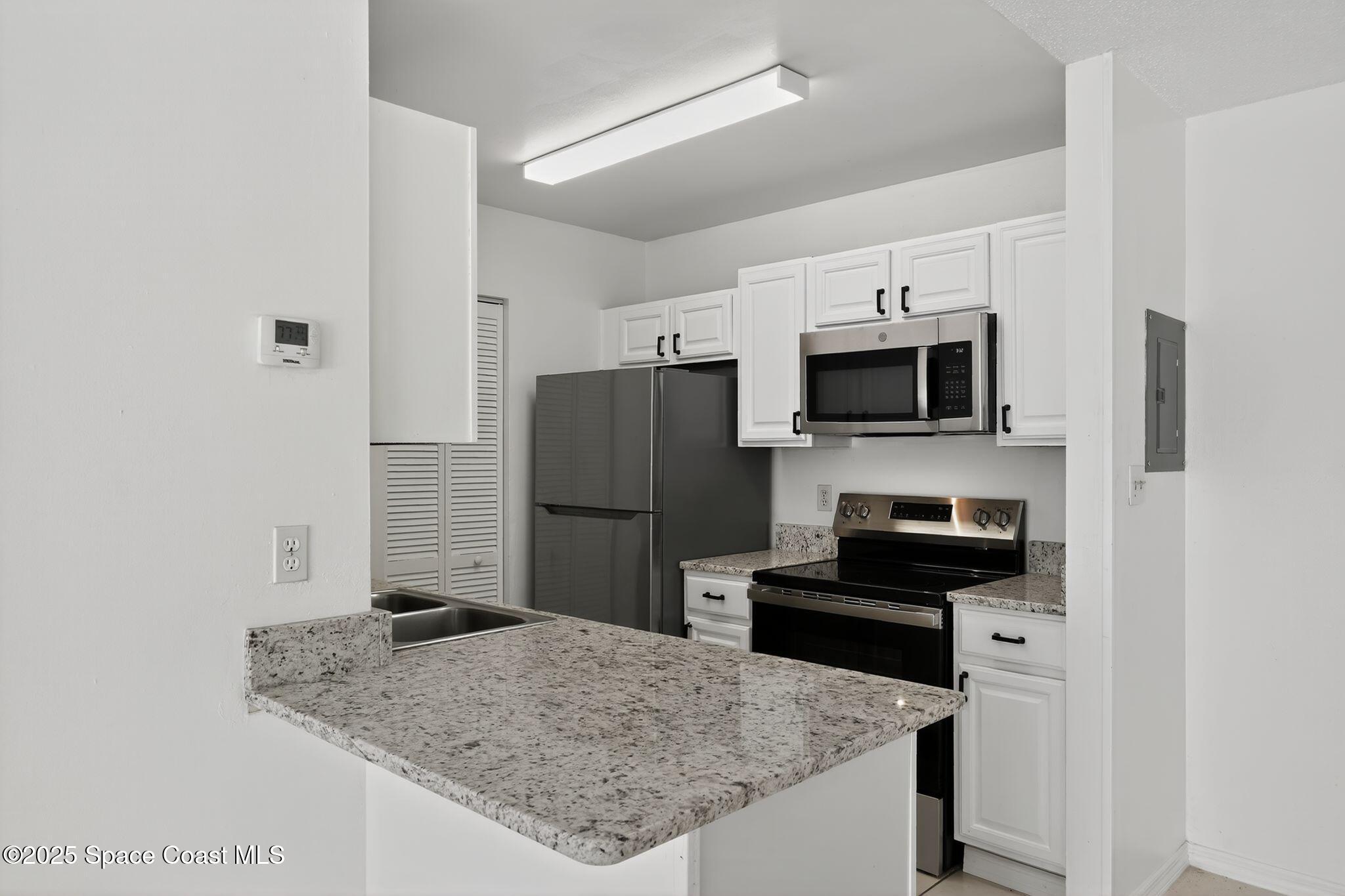 410 Thor Avenue Southeast, Unit 103 Palm Bay, FL 32909 - Photo 9 of 19 a kitchen with stainless steel appliances granite countertop a refrigerator a stove a microwave and sink