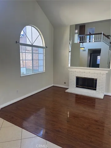an empty room with wooden floor fireplace and windows