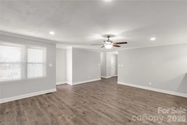 an empty room with chandelier fan and windows