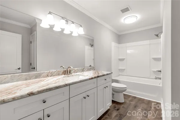 a spacious bathroom with a granite countertop sink a toilet and a bathtub