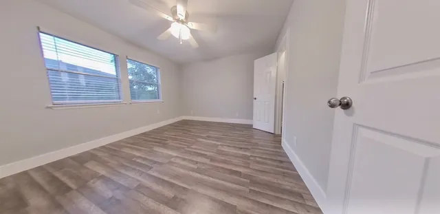 a view of a hallway with wooden floor and a window