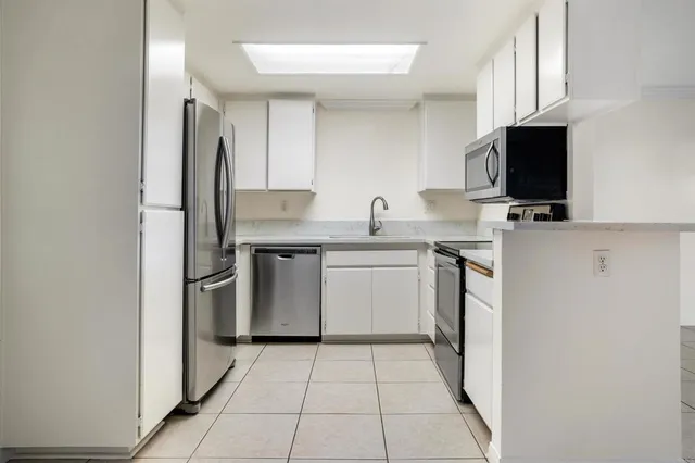 a kitchen with a sink a stove top oven and white stainless steel appliances