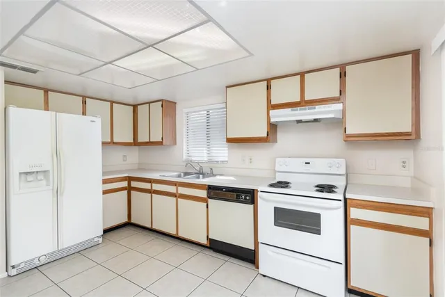 a kitchen with stainless steel appliances granite countertop a sink and dishwasher a refrigerator with white cabinets