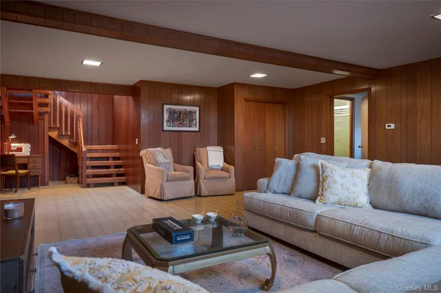 a living room with furniture a glass table and kitchen view