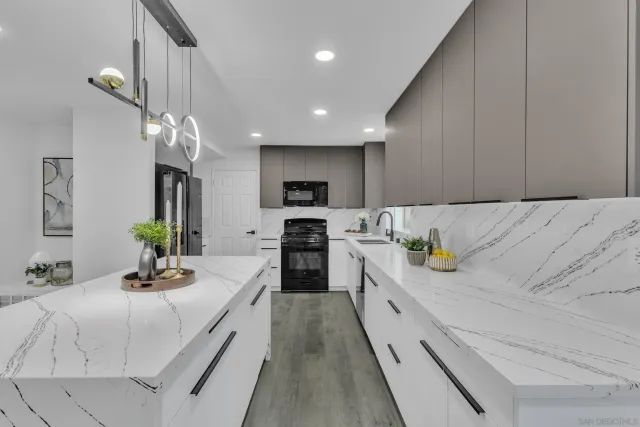 a large white kitchen with a sink and living room view
