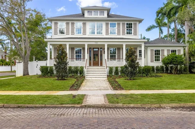 a front view of a house with a yard and potted plants